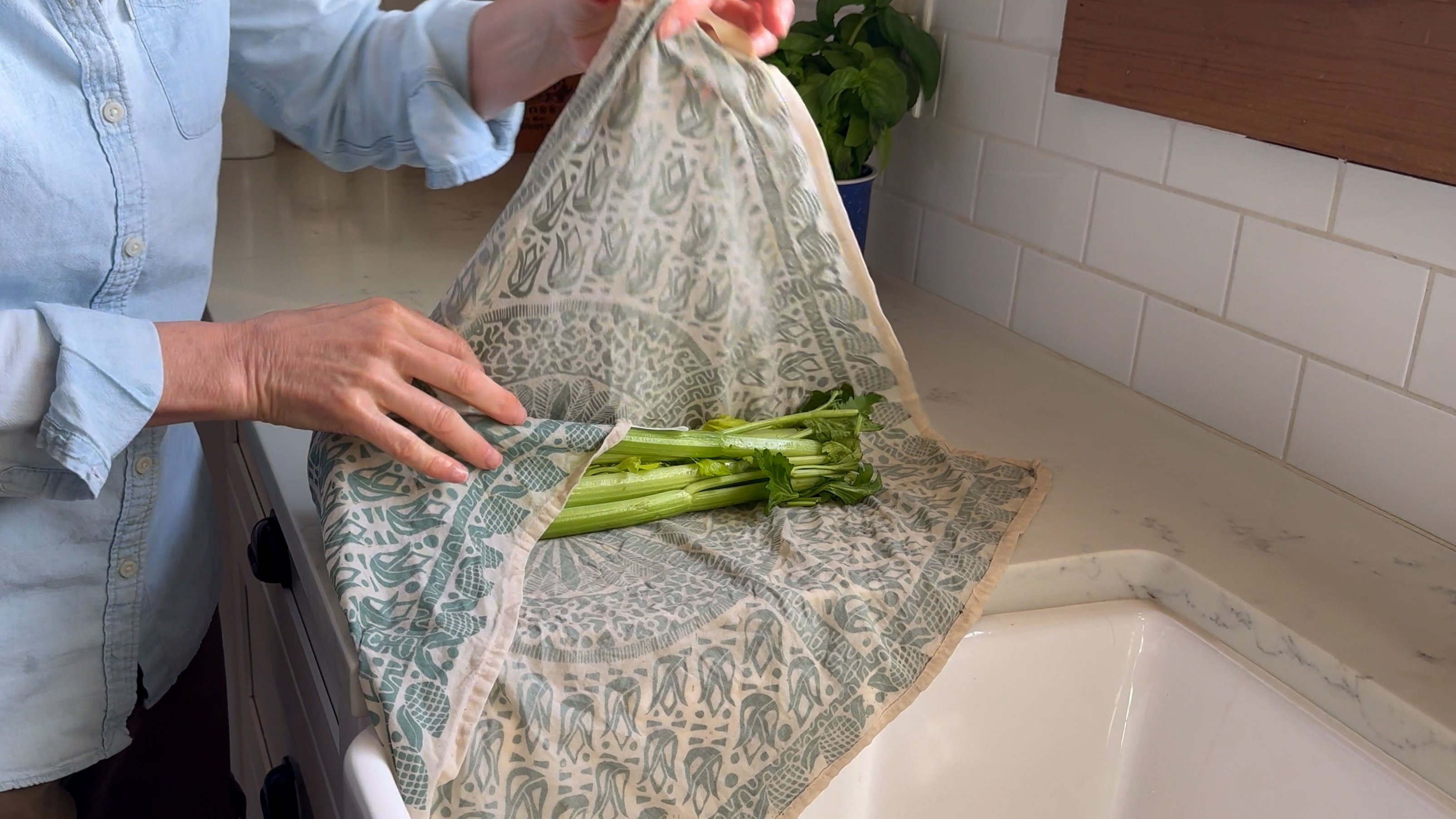 Person holding a bunch of celery on a furoshiki food wrap in the kitchen